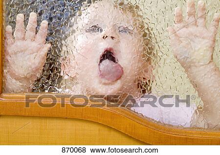 Stock Photo - A child licking a beveled glass window. Fotosearch