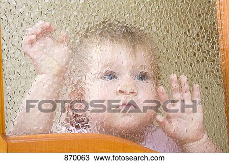 Stock Image - A child pressed up against a beveled glass window . Fotosearch