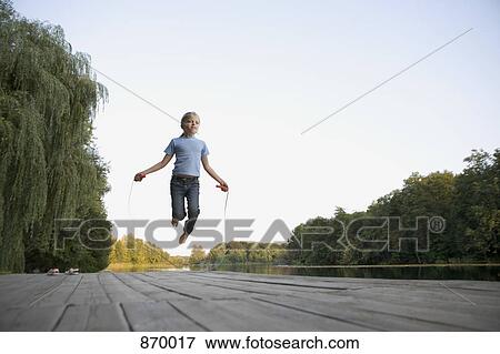 A girl skipping on a wooden jetty View Large Photo Image Stock Photo - A girl skipping on a wooden jetty. Fotosearch
