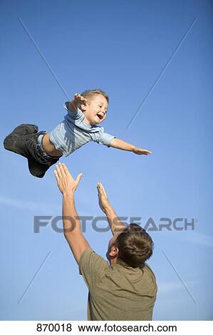 Stock Photo - A man throwing a boy into the air. Fotosearch