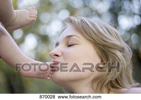 Stock Photo - A mother kissing her baby's toes. Fotosearch