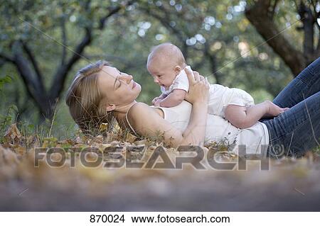 A mother lying on the ground holding her baby View Large Photo Image Picture - A mother lying on the ground holding her baby. Fotosearch