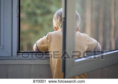 Stock Image - Rear view of a boy looking out a window. Fotosearch