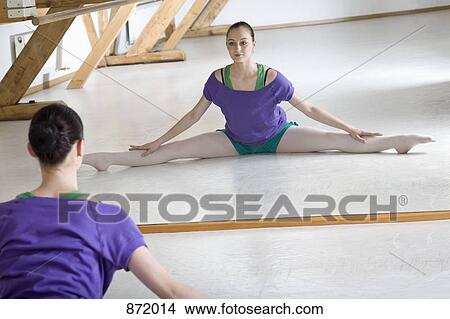 A ballet dancer doing the splits in front of a mirror in a ballet studio View Large Photo Image Picture - A ballet dancer doing the splits in front of a mirror in a ballet studio. Fotosearch