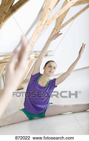Stock Image - A ballet dancer doing the splits in front of a mirror in a ballet studio. Fotosearch