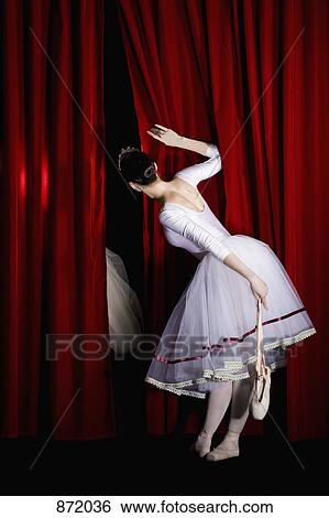A ballet dancer peeking through a stage curtain holding a pointe shoe, rear view View Large Photo Image Stock Photograph - A ballet dancer peeking through a stage curtain holding a pointe shoe, rear view. Fotosearch
