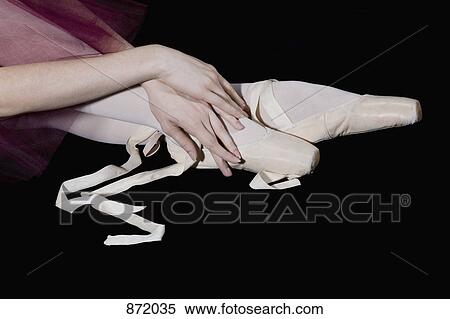 Stock Photography - A ballet dancers hands posed gracefully with her feet in untied pointe shoes. Fotosearch