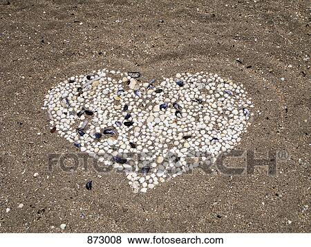 Stock Photo - A heart shape made from seashells on a beach. Fotosearch