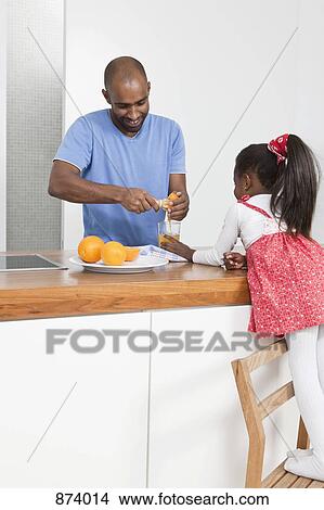 Picture - A father using a wooden juice extractor while his daughter watches. Fotosearch