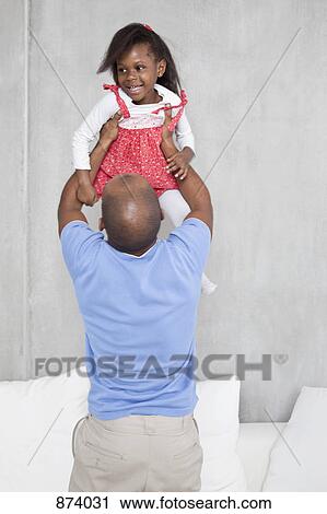 Stock Image - A man holding his daughter aloft. Fotosearch
