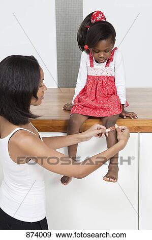 A mother putting a bandage on her daughter's knee View Large Photo Image Stock Photo - A mother putting a bandage on her daughter's knee. Fotosearch