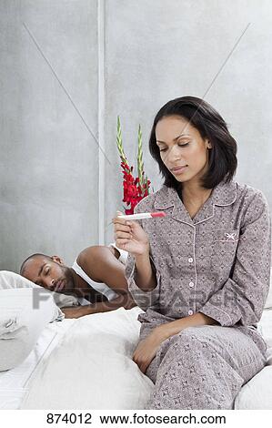 A woman looking at a pregnancy test while her boyfriend sleeps View Large Photo Image Stock Image - A woman looking at a pregnancy test while her boyfriend sleeps. Fotosearch