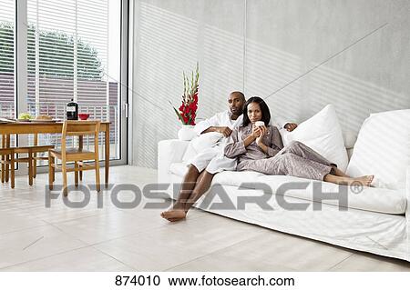A young couple relaxing on a sofa, morning View Large Photo Image Stock Image - A young couple relaxing on a sofa, morning. Fotosearch