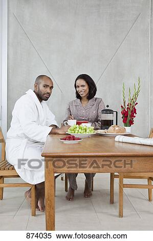 A young couple sitting at a table for breakfast View Large Photo Image Stock Photography - A young couple sitting at a table for breakfast. Fotosearch
