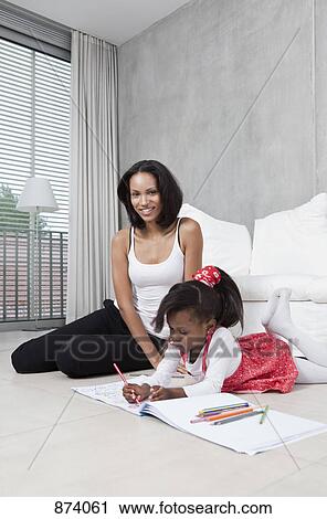 Stock Image - A young girl coloring with her mother. Fotosearch