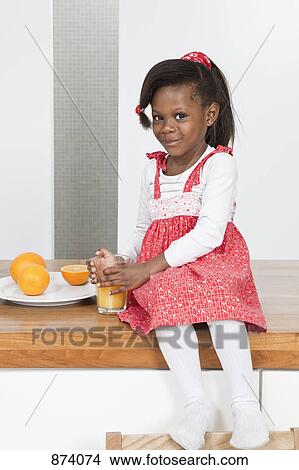 A young girl holding a glass of orange juice, portrait View Large Photo Image Picture - A young girl holding a glass of orange juice, portrait. Fotosearch