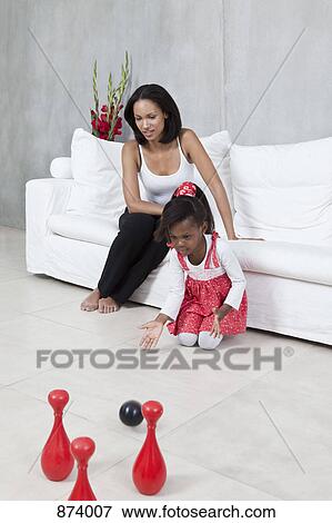 A young girl playing with a toy bowling set while her Mom watches View Large Photo Image Stock Photo - A young girl playing with a toy bowling set while her Mom watches. Fotosearch
