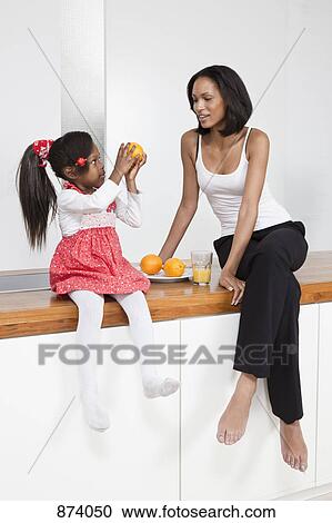 A young girl showing an orange to her mother View Large Photo Image Stock Image - A young girl showing an orange to her mother. Fotosearch