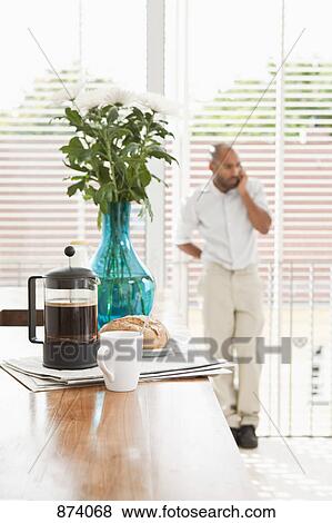 Breakfast on a kitchen counter and a man using a phone in the background View Large Photo Image Stock Photo - Breakfast on a kitchen counter and a man using a phone in the background. Fotosearch