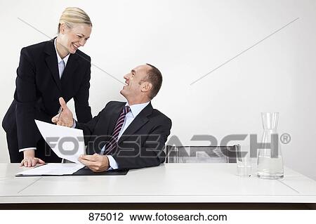 Stock Image - A man and a woman laughing at a desk. Fotosearch