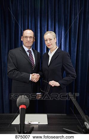 A man and a woman shaking hands at a press conference View Large Photo Image Stock Photo - A man and a woman shaking hands at a press conference. Fotosearch