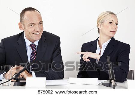A man and a woman sitting at a desk with microphones View Large Photo Image Stock Image - A man and a woman sitting at a desk with microphones. Fotosearch