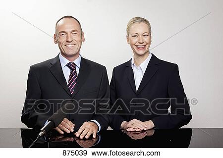 A man and a woman sitting at a desk with a microphone View Large Photo Image Stock Photo - A man and a woman sitting at a desk with a microphone. Fotosearch