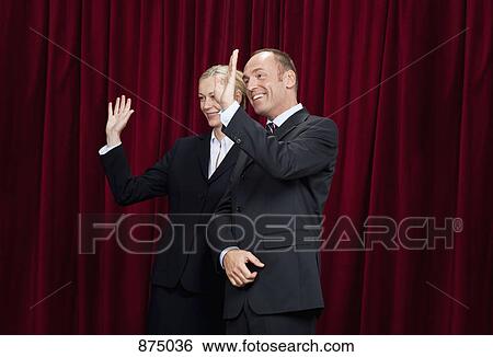 Stock Photograph - A man and a woman waving from a stage. Fotosearch
