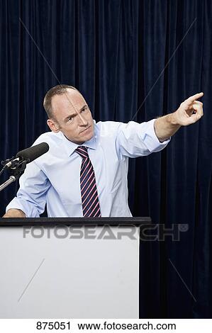 A man gesturing at a lectern View Large Photo Image Stock Image - A man gesturing at a lectern. Fotosearch