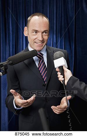 Stock Photography - A man in a suit being interviewed by the media. Fotosearch