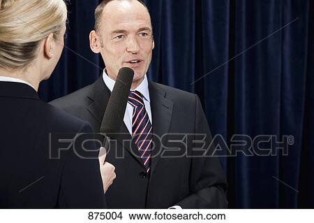 Picture - A man in a suit being interviewed. Fotosearch