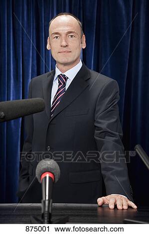 A man in a suit standing at a lectern View Large Photo Image Stock Image - A man in a suit standing at a lectern. Fotosearch