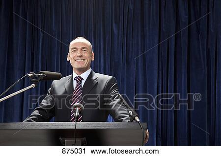 A man in a suit standing at a lectern View Large Photo Image Stock Image - A man in a suit standing at a lectern. Fotosearch