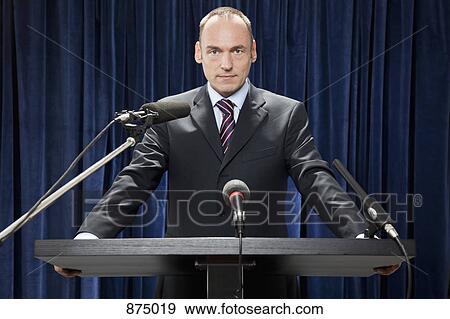 A man in a suit standing at a lectern View Large Photo Image Stock Photo - A man in a suit standing at a lectern. Fotosearch