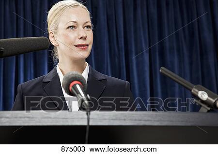 Stock Image - A woman in a suit at a lectern. Fotosearch