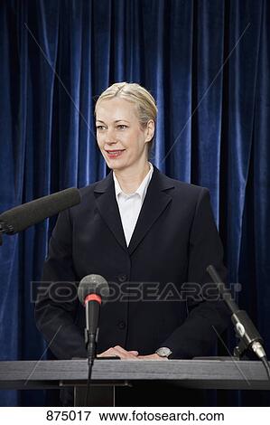A woman in a suit standing at a lectern View Large Photo Image Stock Photo - A woman in a suit standing at a lectern. Fotosearch