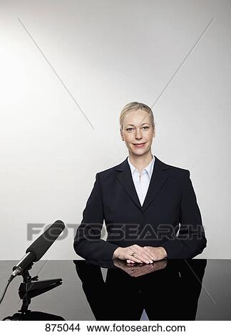 A woman sitting at a desk with a microphone View Large Photo Image Picture - A woman sitting at a desk with a microphone. Fotosearch