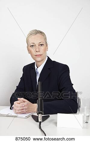 A woman sitting at a desk with a microphone View Large Photo Image Stock Image - A woman sitting at a desk with a microphone. Fotosearch
