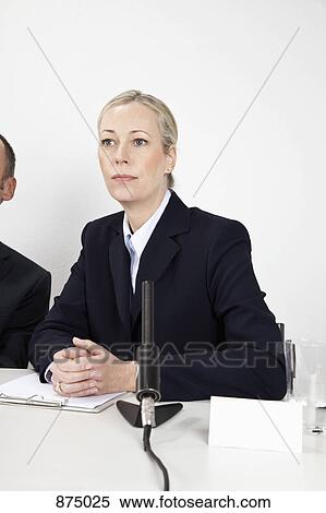 A woman sitting at a desk with a microphone View Large Photo Image Stock Photography - A woman sitting at a desk with a microphone. Fotosearch