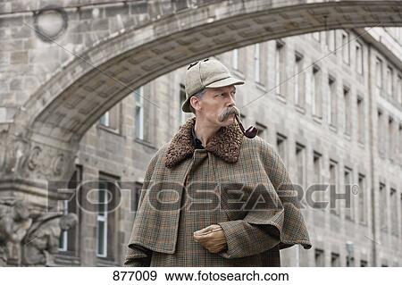 A man dressed up as Sherlock Holmes standing under a building arch looking away View Large Photo Image Stock Photo - A man dressed up as Sherlock Holmes standing under a building arch looking away. Fotosearch