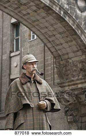 A man dressed up as Sherlock Holmes standing under a building arch looking away View Large Photo Image Stock Photo - A man dressed up as Sherlock Holmes standing under a building arch looking away. Fotosearch