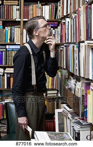 Stock Photograph - A man scrutinizing books in a bookstore. Fotosearch