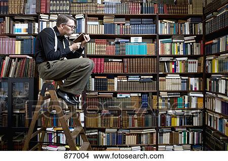 Picture - A man sitting on a ladder in a bookstore reading a book. Fotosearch