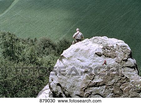 Stock Image - A rock climber sitting at the top of a rock. Fotosearch