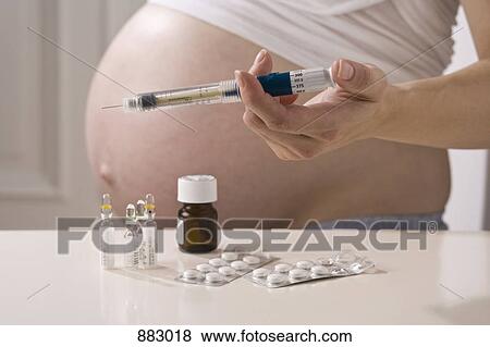 A pregnant woman holding a syringe above other prenatal medicines, focus on hand View Large Photo Image Stock Photo - A pregnant woman holding a syringe above other prenatal medicines, focus on hand. Fotosearch