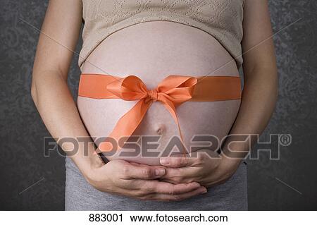 A ribbon tied in a bow around a pregnant belly, midsection, focus on abdomen View Large Photo Image Stock Image - A ribbon tied in a bow around a pregnant belly, midsection, focus on abdomen. Fotosearch