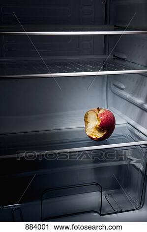 Stock Image - A half eaten apple in an empty refrigerator. Fotosearch
