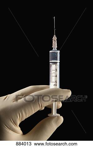Stock Image - Detail of a hand holding a syringe. Fotosearch