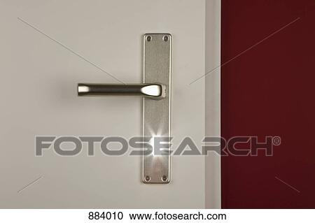 Stock Image - Detail of a light shining through the keyhole of a door. Fotosearch