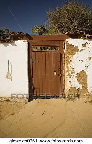 Stock Image - Facade of a wooden door in a stucco wall. Fotosearch